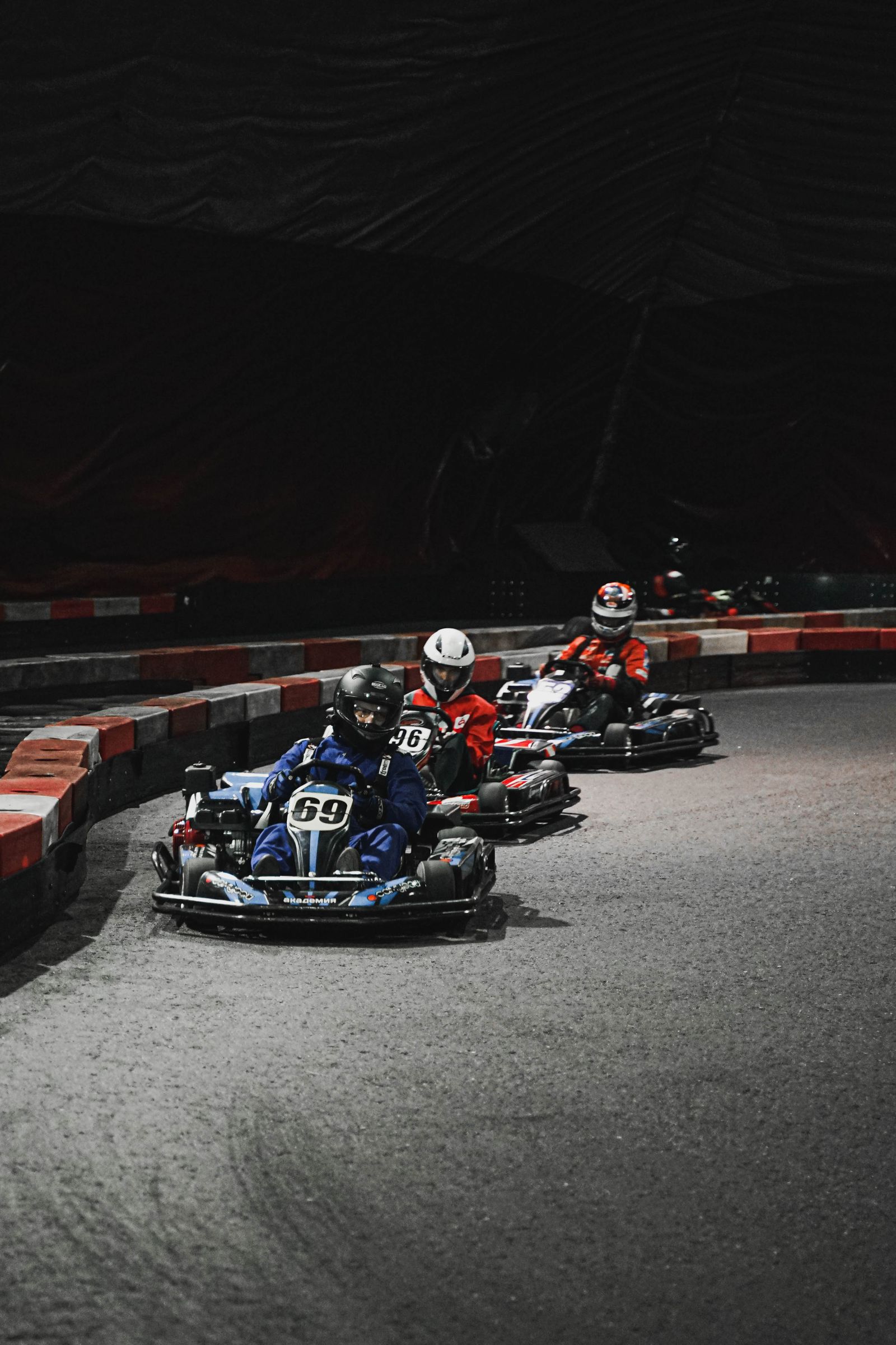 Trois karts en piste dans un circuit couvert.